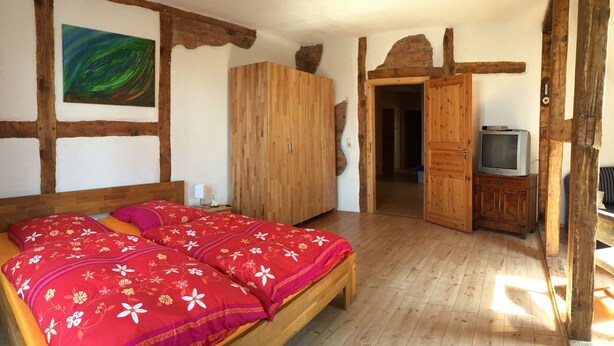 Une chambre à coucher avec un lit en bois, une armoire, un téléviseur et un tableau accroché au mur.