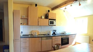 Une cuisine avec des meubles de rangement en bois, un four à micro-ondes, un évier et une table à manger.