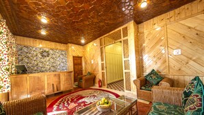 A cozy room with wicker furniture, a glass coffee table with fruit, and a patterned rug. - Gulmarg Ski Hill Resort (Baramula)