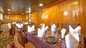 A restaurant with wooden walls and tables set for dining, featuring plaid tablecloths and white napkins. - Gulmarg Ski Hill Resort (Baramula)