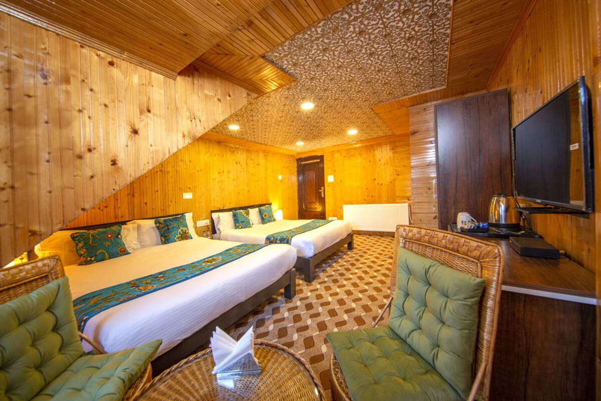 Quarto de hotel com duas camas, televisão e uma janela grande.
