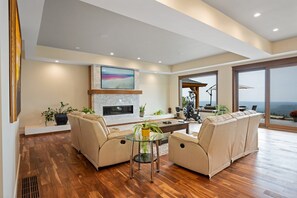Relax in a spacious living area with a high ceiling, featuring a large flat-screen TV above a fireplace and a comfortable sofa set.