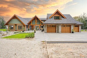 Stunning multi-story house with a symmetrical design and central entrance, set amidst a well-maintained lawn and gravel driveway.
