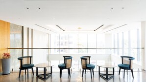 A modern hotel lobby with a glass partition, a round table, and four chairs. - Signature Hotels (Visakhapatnam)