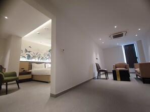 A modern hotel room with a bed, two armchairs, a small table, and a wall with a tropical mural. - Signature Hotels (Visakhapatnam)