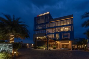 A modern hotel with a glass facade, illuminated signage, and a well-lit entrance. - Signature Hotels (Visakhapatnam)