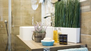 Ein Badezimmer mit einem Holzkosmetikschrank, einer Dusche und einer Topfpflanze.