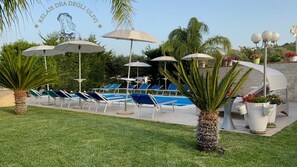 Relax by the pool surrounded by lush greenery and palm trees.