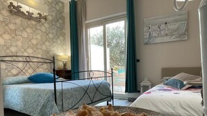 Un dormitorio con dos camas, un ventanal grande y un plato de pasteles sobre una mesa.