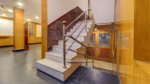 Un escalier avec des marches en marbre et des rampes en métal, menant à un niveau inférieur.