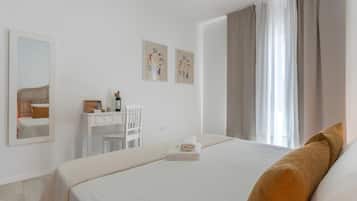 Une chambre d’hôtel avec un lit, un bureau, une chaise, un miroir et des œuvres d’art accrochées au mur.