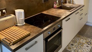 Une cuisine moderne équipée d’un four en acier inoxydable, d’un grille-pain encastré et d’une planche à découper en bois.