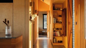 Un intérieur moderne avec un plancher en bois, un coin cuisine doté d’un comptoir et de placards, et une bibliothèque.