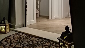 Un pasillo con piso de madera, un tapete estampado y una escalera que lleva a otra habitación.