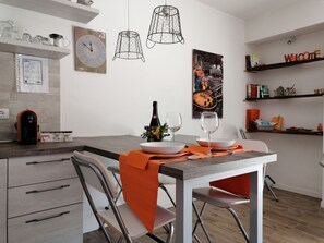 Une cuisine moderne avec un coin repas, comprenant une machine à café, des verres à vin et une horloge murale.