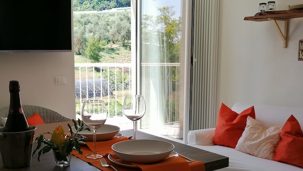Un comedor con una mesa dispuesta para dos personas, una botella de vino y un bol.