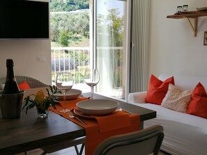 Un comedor con una mesa dispuesta para dos personas, una botella de vino y un bol.