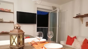 Un comedor con una mesa de madera dispuesta para dos personas, un farol y un sofá con cojines rojos.