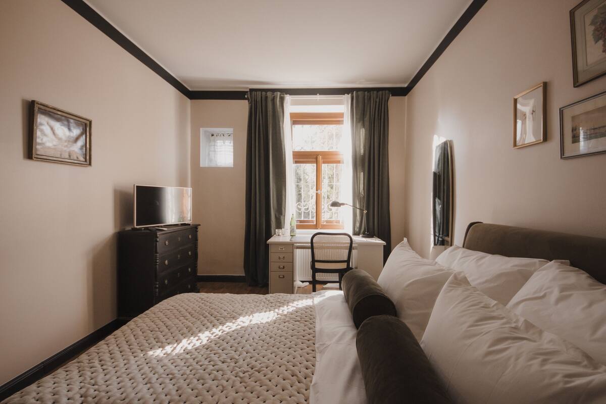 Un dormitorio con cama, escritorio, silla, cómoda y televisor.
