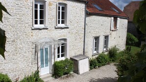 Un bâtiment en pierre doté de nombreuses fenêtres, une allée en gravier et un petit jardin.