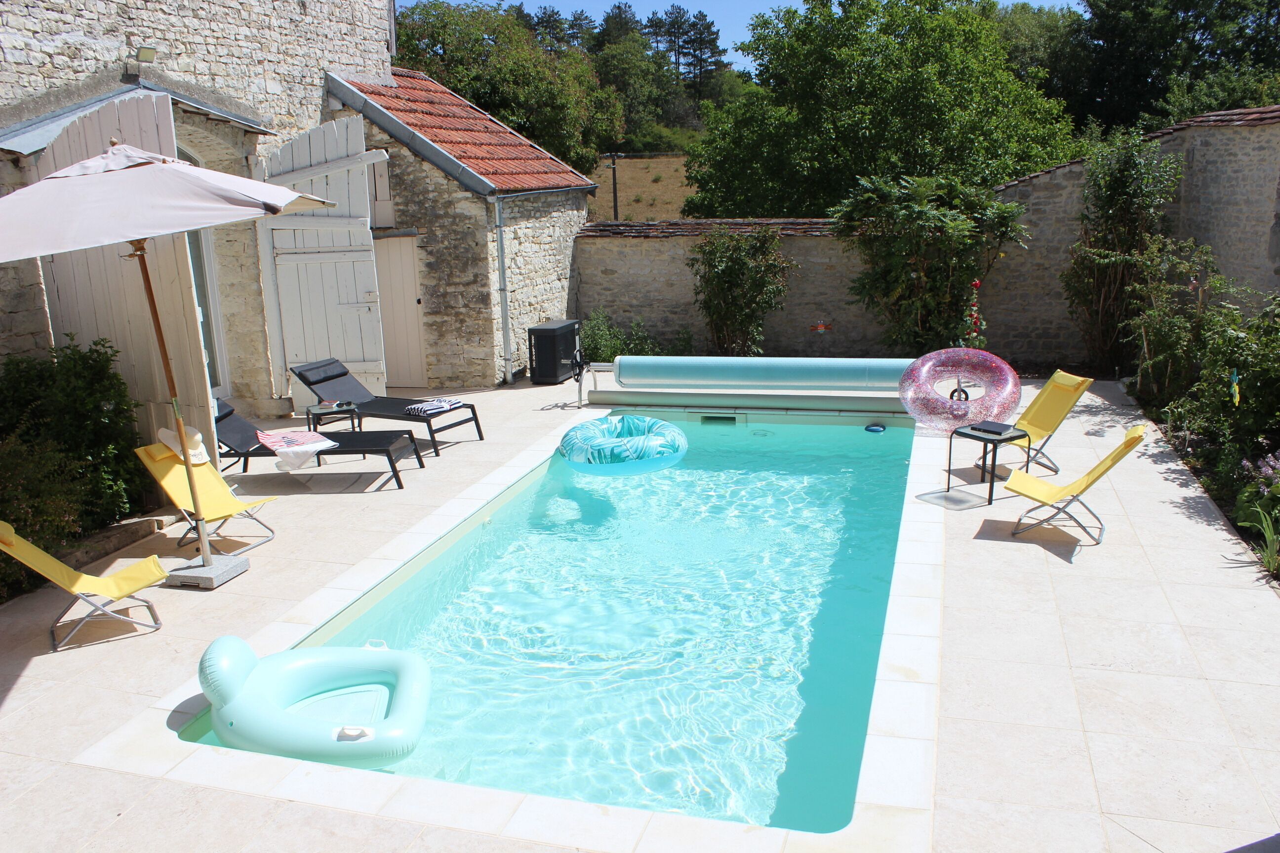 Une piscine équipée de chaises longues, d’un parasol et d’un toboggan aquatique.