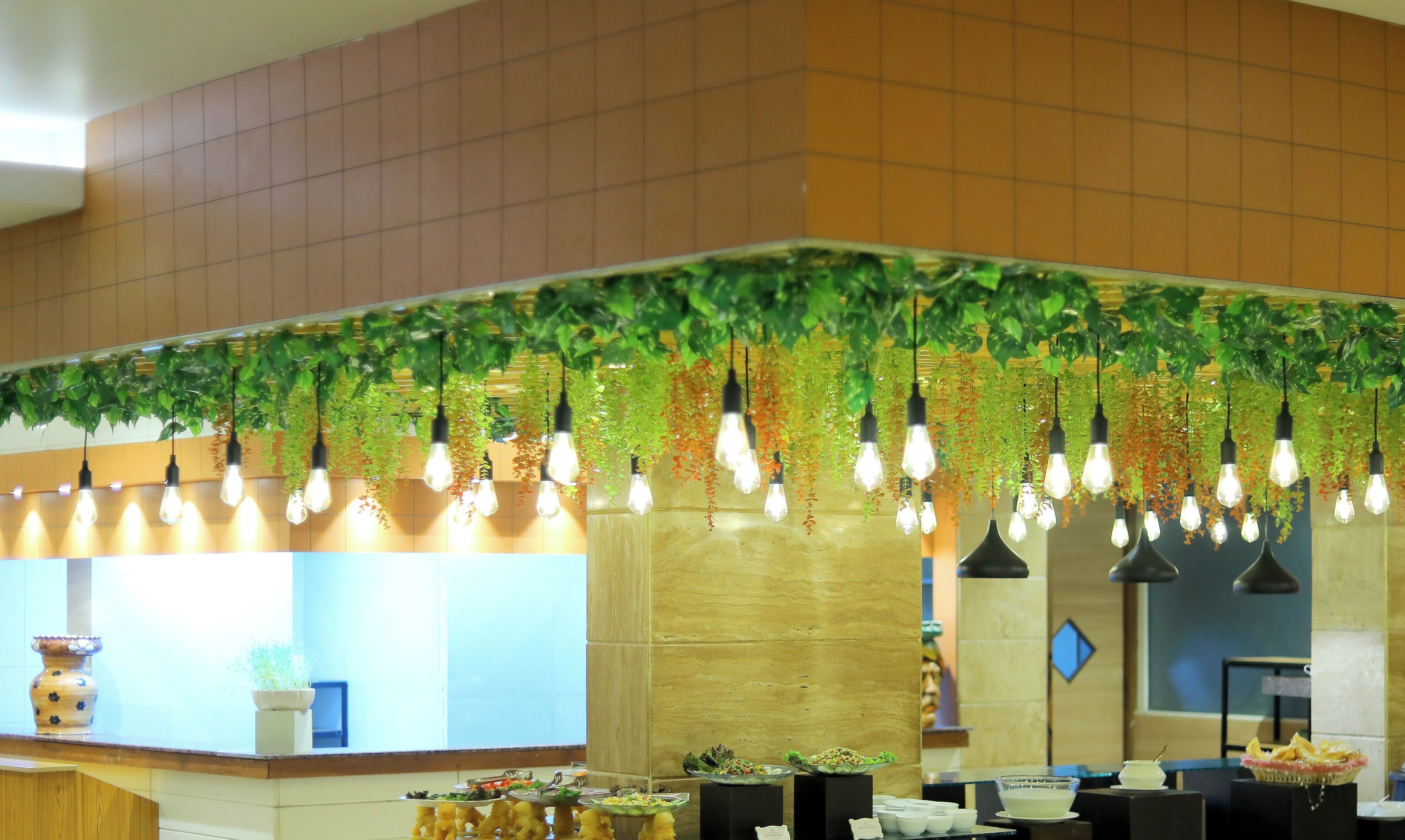 Un vestíbulo de hotel con plantas colgantes e iluminación.
