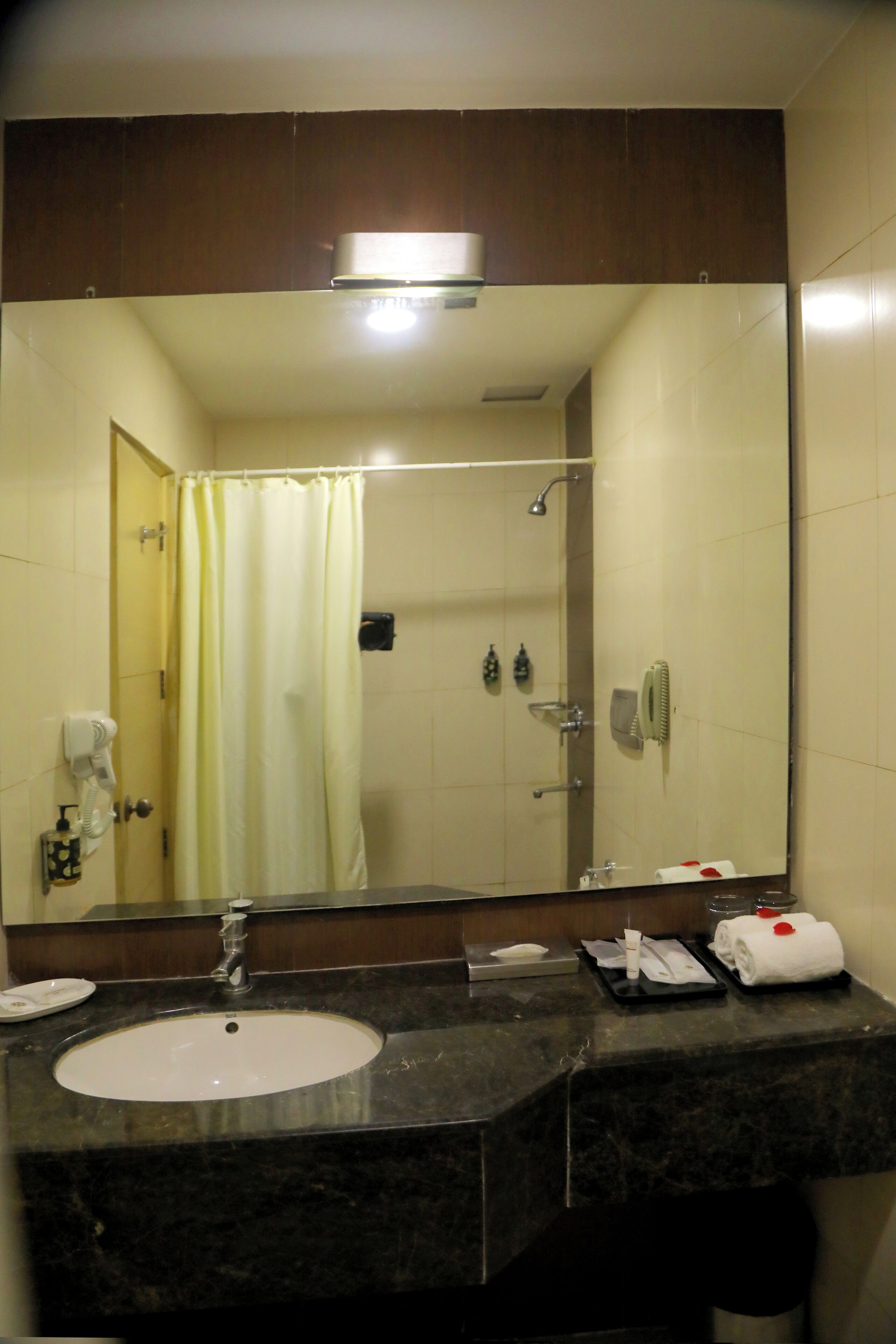 Un baño con un espejo grande, un lavabo, una ducha y un perchero para toallas.