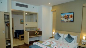 Une chambre d’hôtel avec un lit, un bureau, une chaise, une armoire et un tableau au mur.