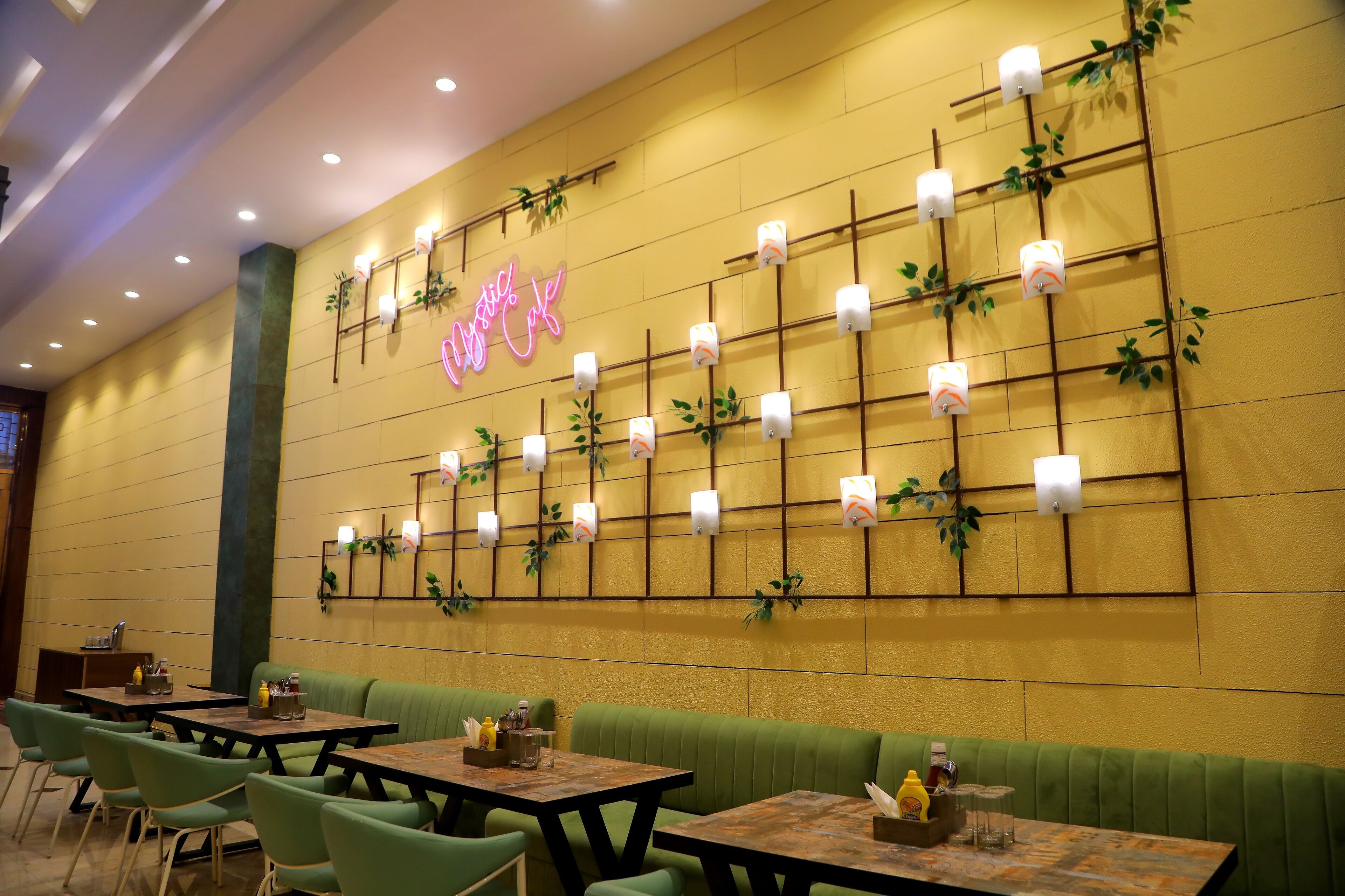 Un interior de restaurante con asientos tipo cabina verdes, mesas de madera y un letrero de neón en la pared.