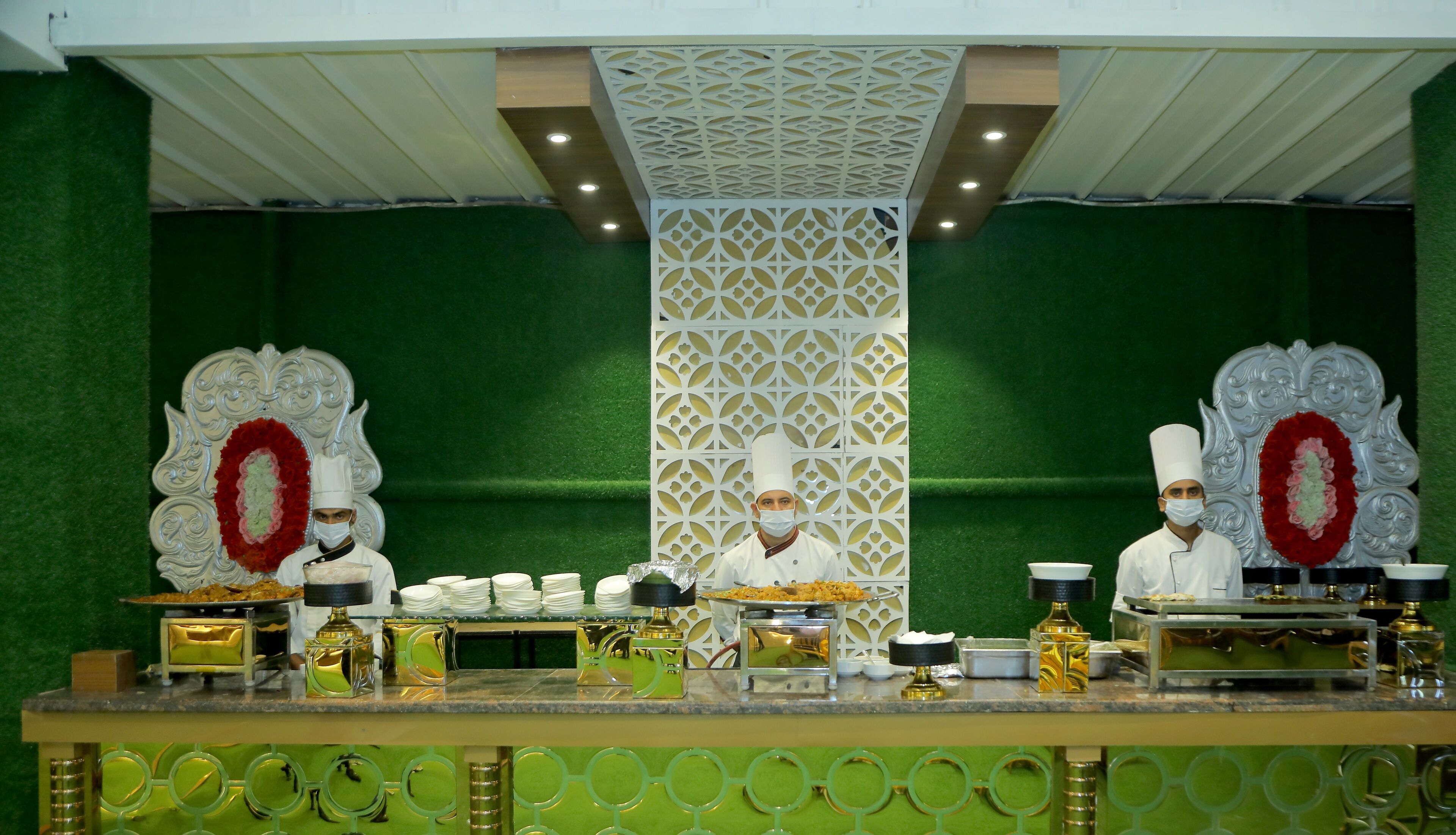 A formal dining setup with two waiters, a decorative backdrop, and a variety of dishes and utensils.