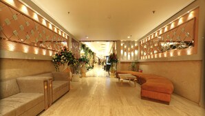 Un hall d’entrée spacieux, avec un canapé beige, un fauteuil incurvé et une table basse.