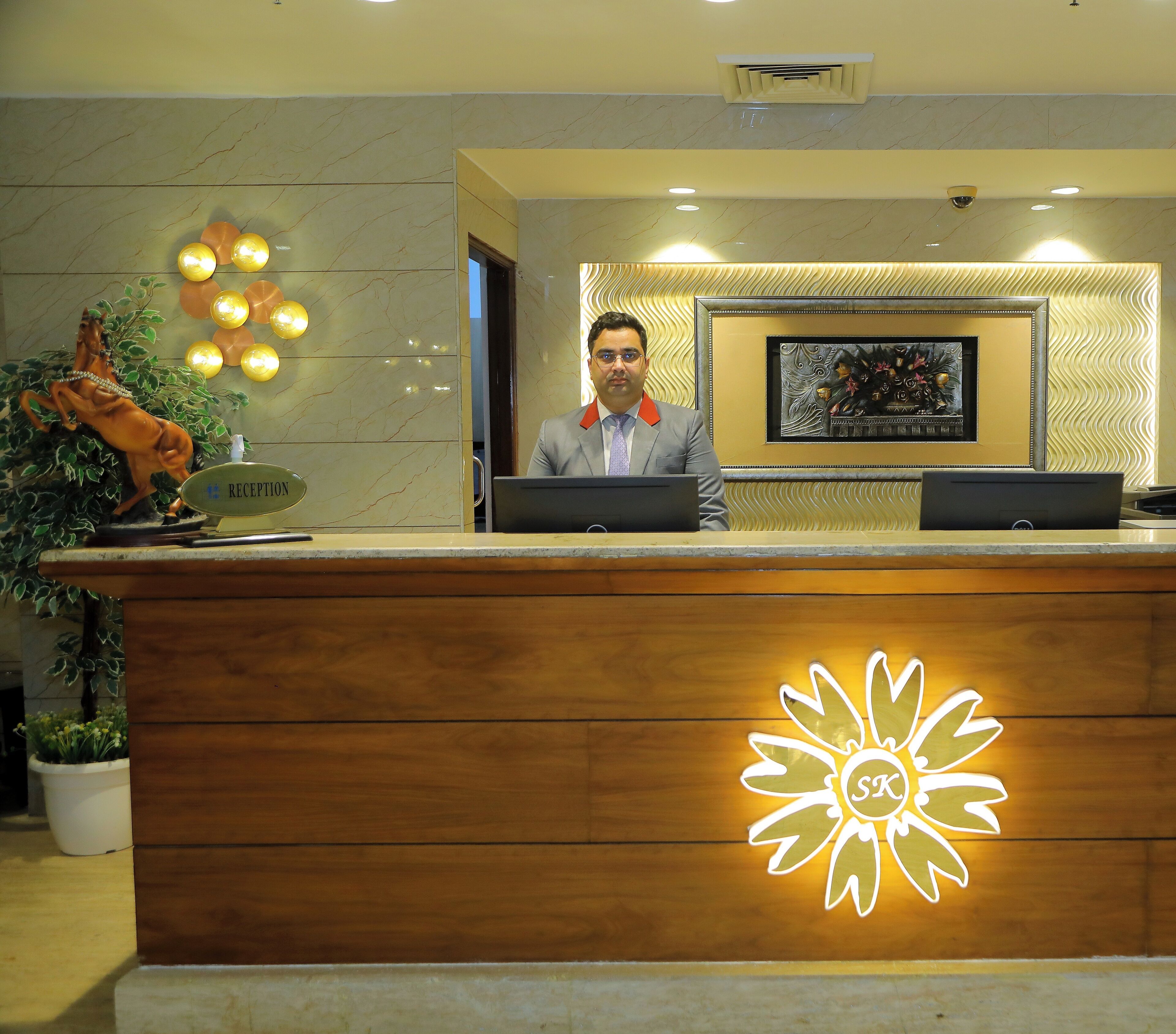 A reception desk with a marble wall, a framed artwork, and a statue of a horse.