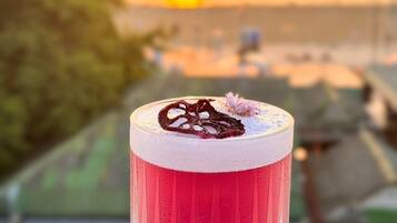 A clear glass with a red beverage, possibly a cocktail, on a wooden coaster.