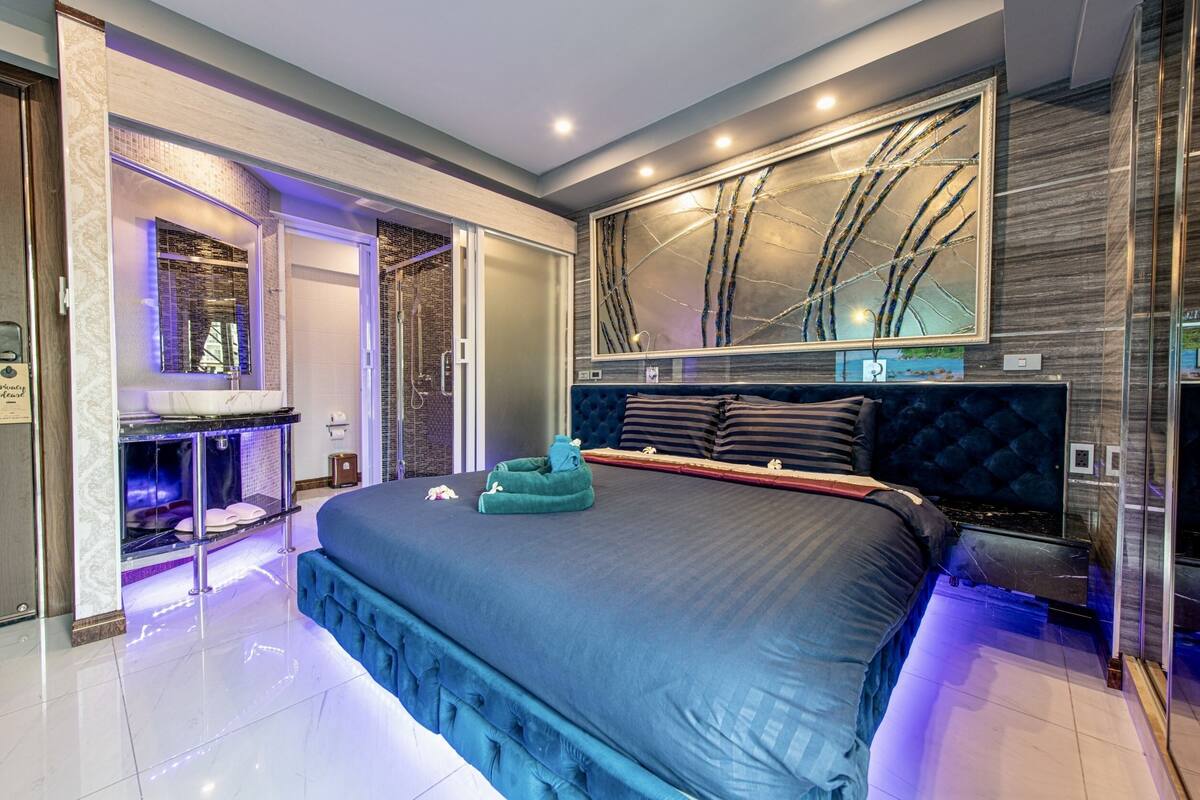Une chambre moderne avec un grand lit, une coiffeuse intégrée et un grand miroir.