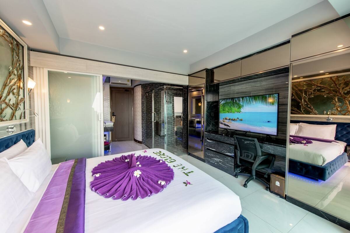 Une chambre d’hôtel moderne dotée d’un grand lit, d’une télévision et d’une douche à parois de verre.