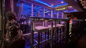 Een bar met een Boeddhabeeld, barkrukken en een bord waarop 
