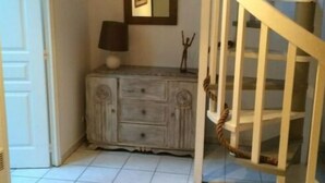 A staircase with a white railing, a wooden cabinet with drawers, a lamp, and a framed picture on the wall. - Touquettoise 'Romeo (Paris)