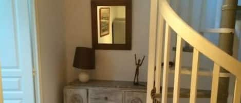 Eine Treppe mit weißer Geländer, eine Holzkabine mit Schubladen, eine Lampe und ein gerahmtes Bild an der Wand.