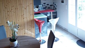 Una cocina moderna con paneles de madera, un comedor con mesa redonda y sillas, y un ventanal que proporciona luz natural.