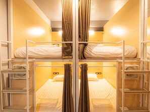 Een studentenkamer met stapelbedden, een verwarming en een spiegel.