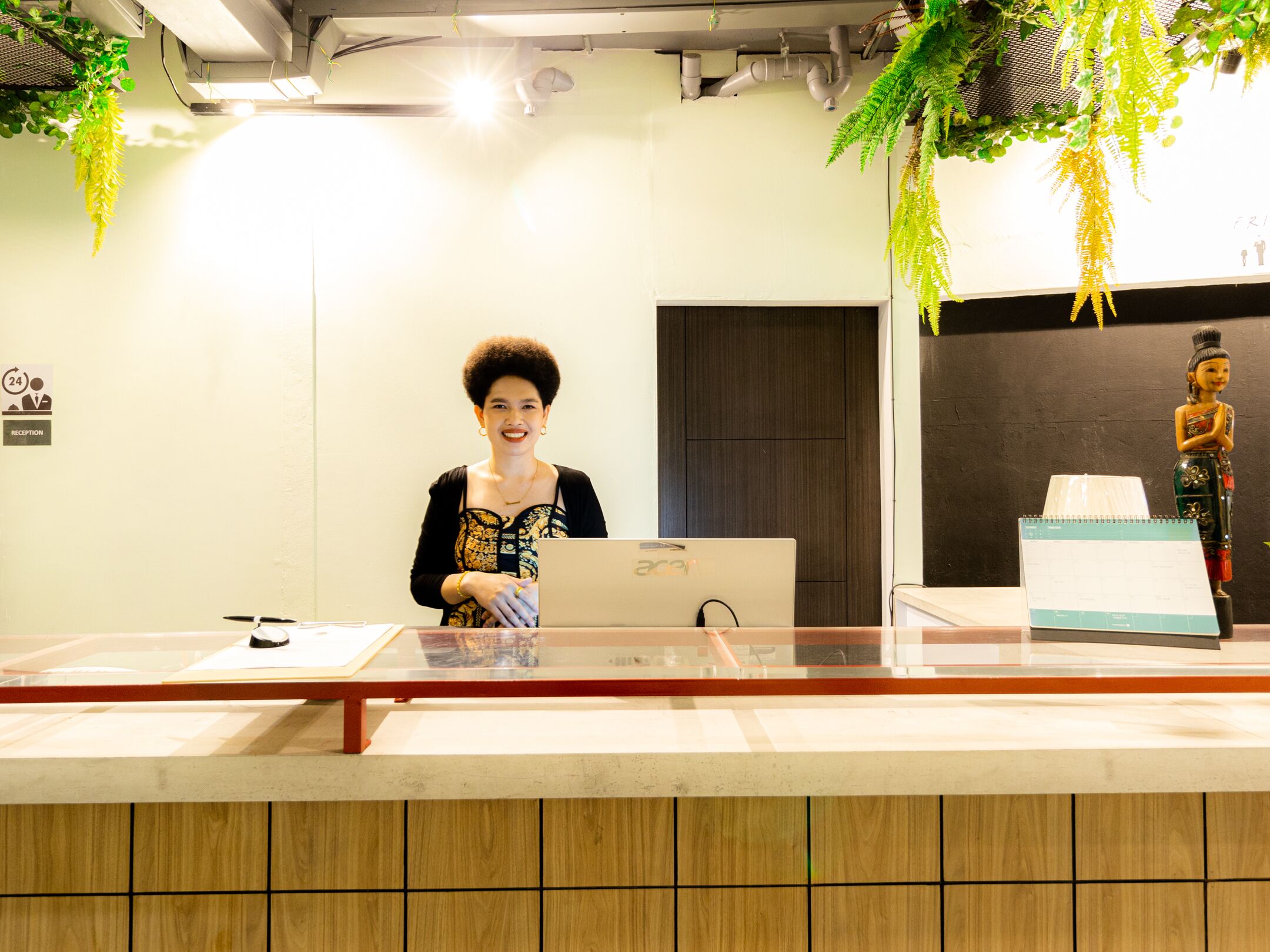 A reception desk with a laptop, a calendar, and a decorative statue.