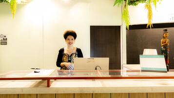 A reception desk with a laptop, a calendar, and a decorative statue.