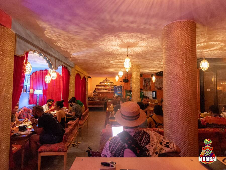 An indoor dining area with tables and chairs, a bar area with a counter, and hanging lights.