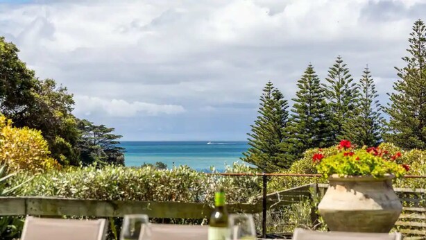 An outdoor dining area with a table set for two, overlooking a coastal view with trees and a body of water. - Horizon View Retreat by Ready Set Stay - Beach Views (Sorrento)