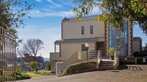 A building with a staircase leading to a gated entrance, surrounded by greenery and a clear sky. - Horizon View Retreat by Ready Set Stay - Beach Views (Sorrento)
