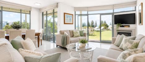 A spacious living room with a large TV, comfortable seating, and a view of the outdoors.
