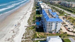 A beachfront hotel with multiple buildings, a parking lot, and a beach.