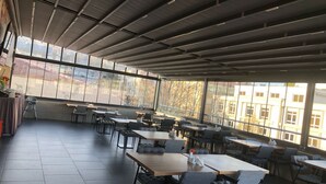 Un comedor amplio y luminoso en el interior, con ventanas grandes, mobiliario moderno y techo alto.