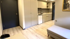 Una cocina compacta con armarios blancos, una pequeña encimera y suelo de madera.