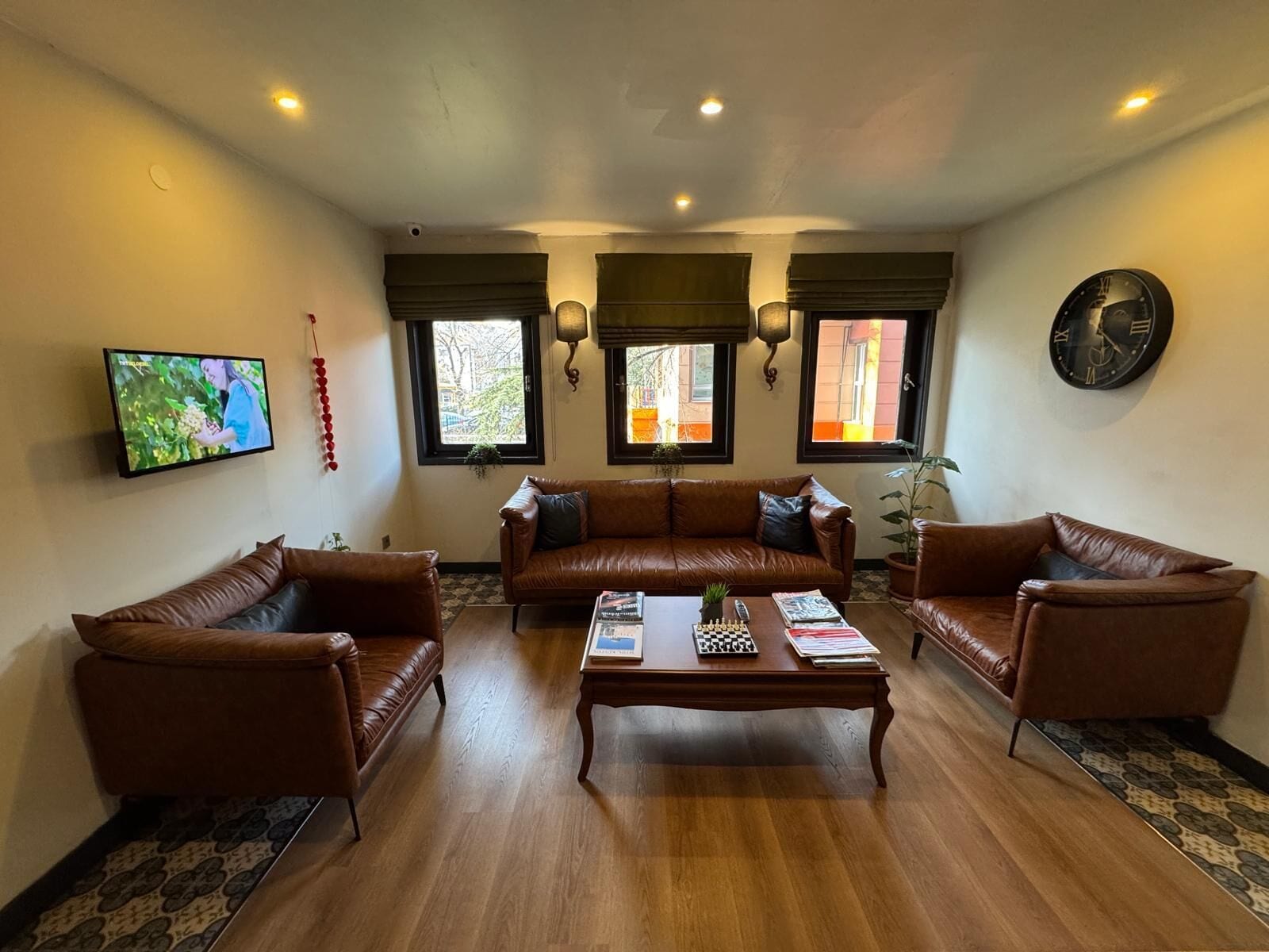 Una sala de estar con un sofá de cuero marrón, una mesa de centro de madera y un televisor montado en la pared.
